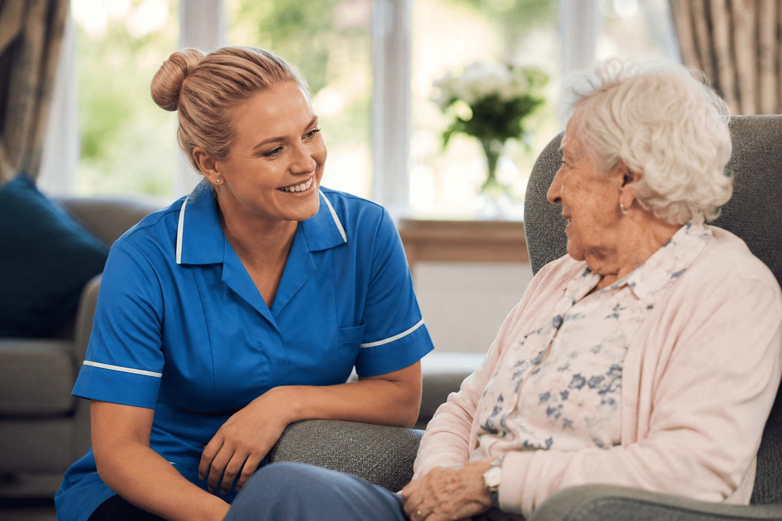 Healthcare Assistant Care Home — Advantage Angels female healthcare assistant in blue uniform caring for elderly resident in UK care home